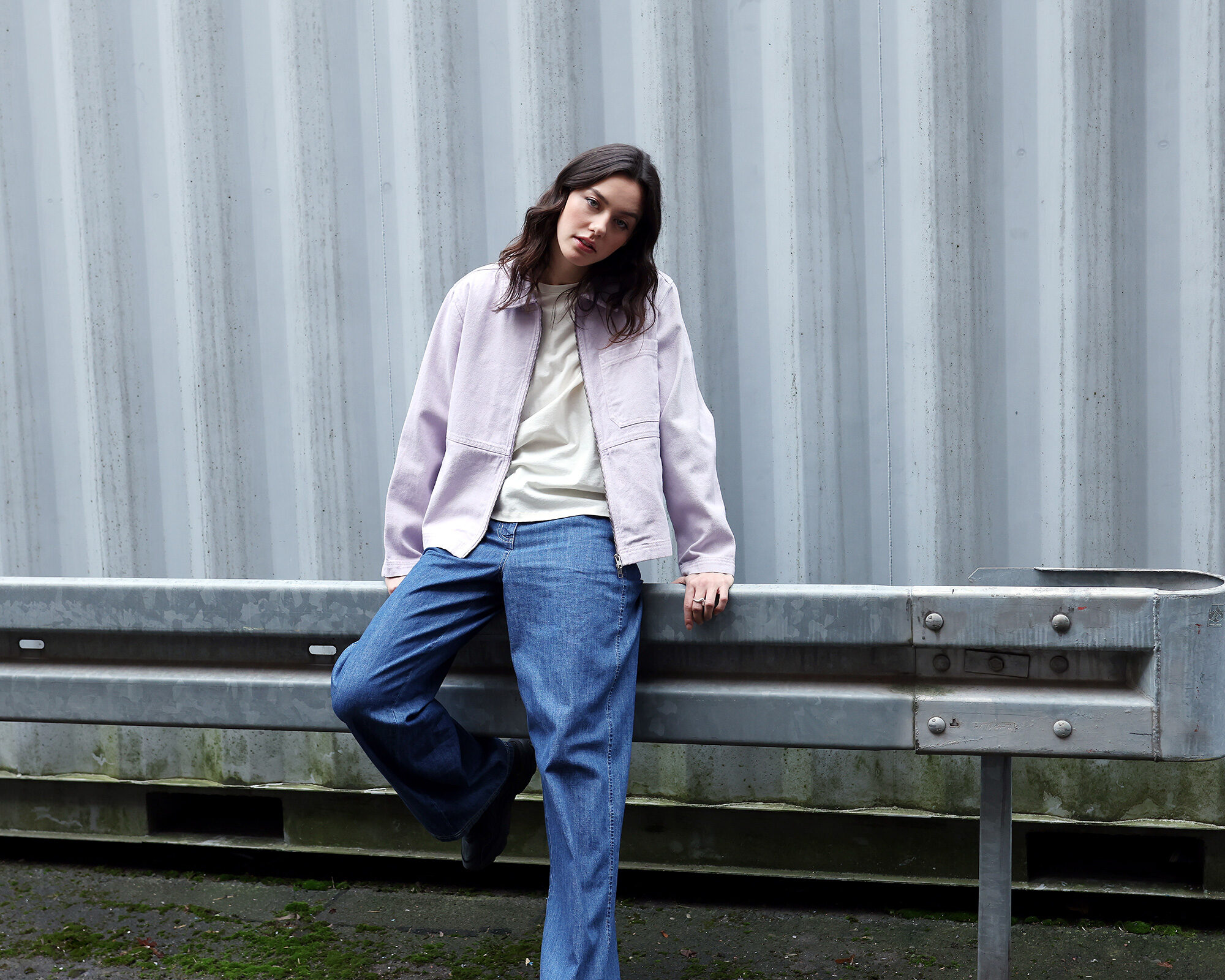 Frau in bunter Kapuzenjacke und Jeans sitzend